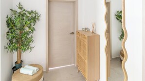Een kamer met een houten kast, een spiegel, een deur en een plant in pot.