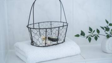 A wire basket with a wooden handle on a white tiled surface.