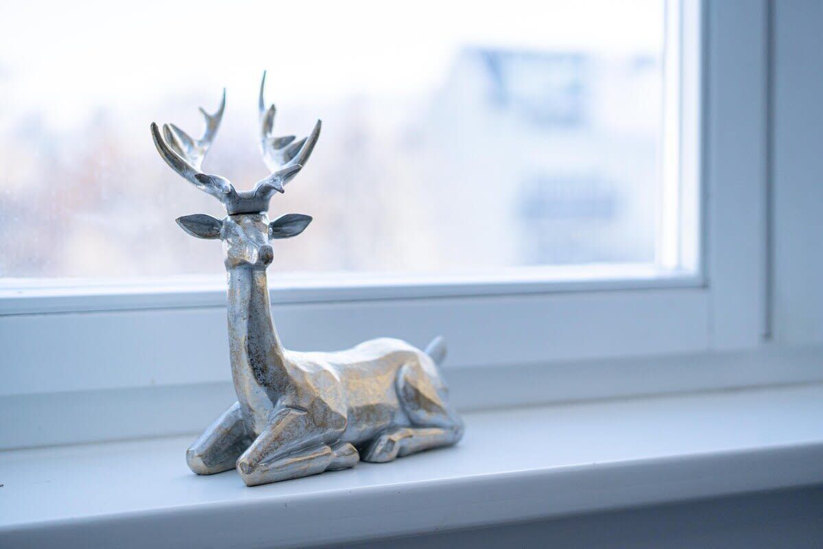 A silver deer figurine on a windowsill.