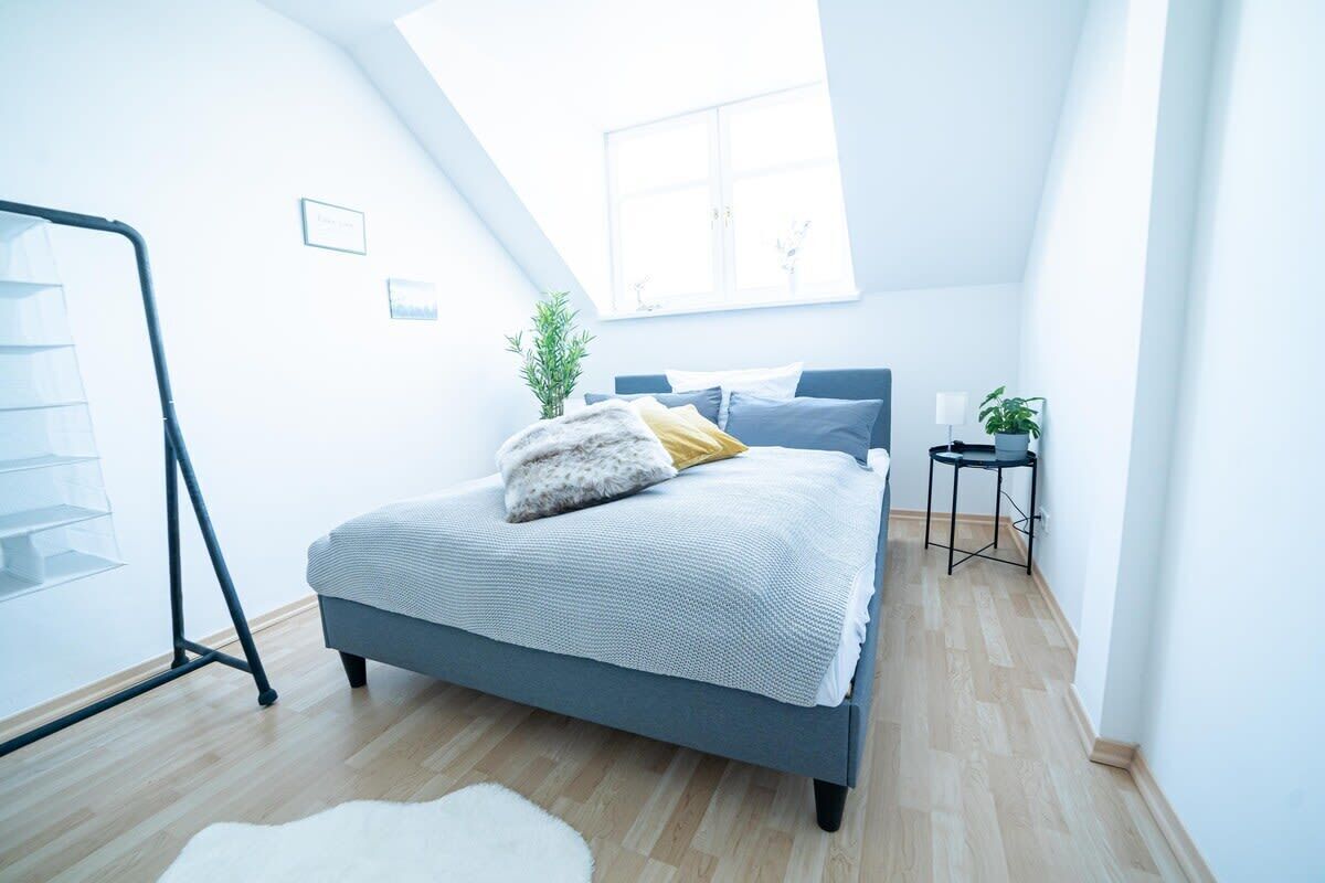 Um quarto moderno com um domo de vidro, uma cama com cabeceira cinza, uma mesinha de cabeceira e uma planta.