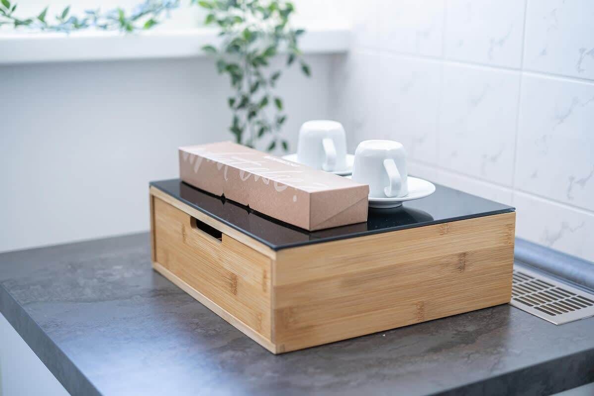 Un piano di lavoro in cucina con una scatola di legno e due tazze bianche.