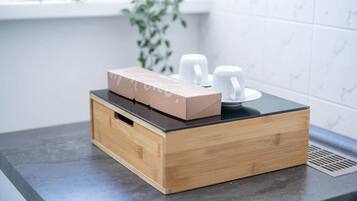 Un piano di lavoro in cucina con una scatola di legno e due tazze bianche.