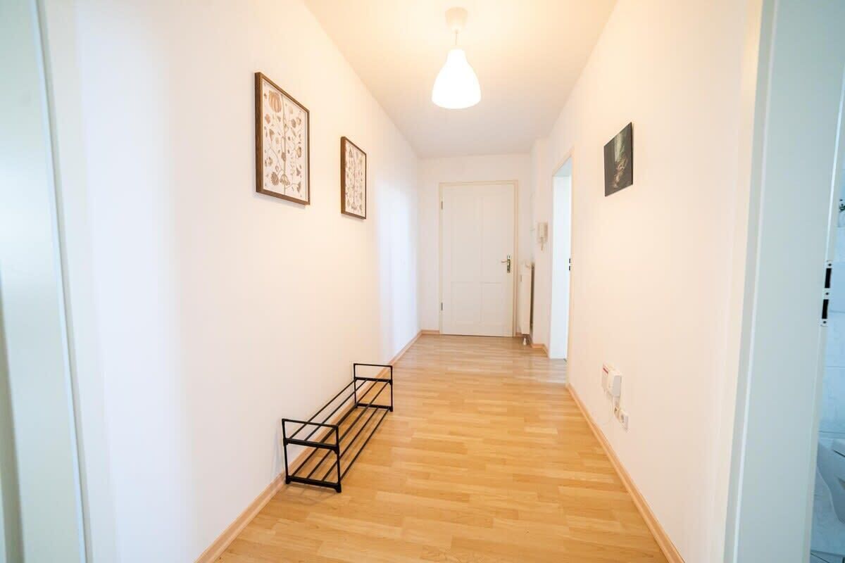 A hallway with wooden flooring, white walls, and framed artwork.