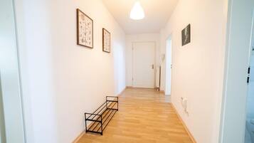 A hallway with wooden flooring, white walls, and framed artwork.