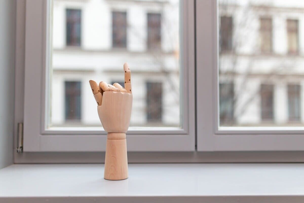 Una figurita de madera sobre un alféizar, con vistas a edificios.
