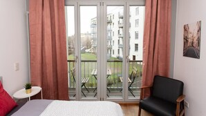 Ein Schlafzimmer mit großem Fenster, einem Bett, einem Sessel und einem kleinen Tisch.