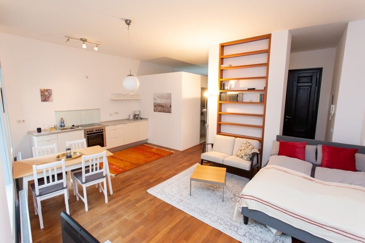 Un espacio habitable compacto con kitchenette, comedor, sofá y cama.