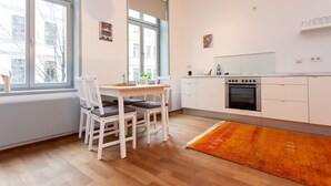 Eine moderne Küche mit weißen Schränken, einem großen Fenster und einem Essbereich mit Tisch und Stühlen.