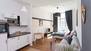 Um apartamento moderno com cozinha compacta, sala de jantar, quarto com cama grande e sofá, e vista para a cidade.