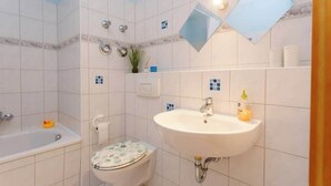 Een badkamer met een bad, toilet en wastafel.