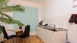 Een kleine keuken met een houten tafel, twee zwarte stoelen, een magnetron en een spoelbak.