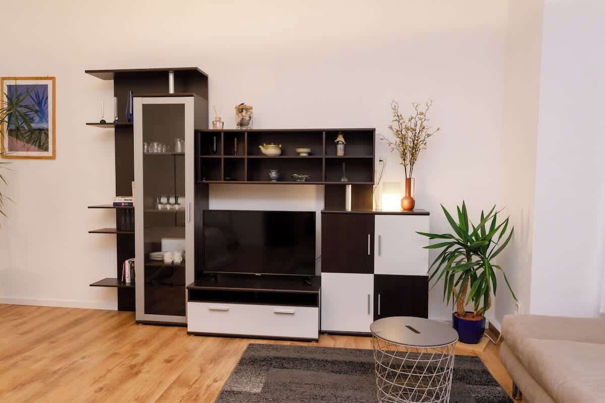 A modern living room with a black and white TV stand, a glass coffee table, and a potted plant.