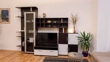 A modern living room with a black and white TV stand, a glass coffee table, and a potted plant.