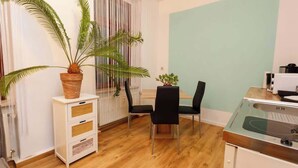 Een knus woongedeelte met een eethoek, een kitchenette en een potplant.