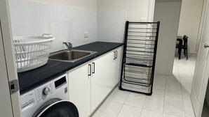 A compact kitchen with a washing machine, a sink, and a drying rack.