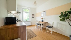 A modern kitchen with a wooden countertop, a black microwave, and a window providing natural light. - FullHouse | Magdeburg | A9-4 | PrimeApartment (Magdeburg)