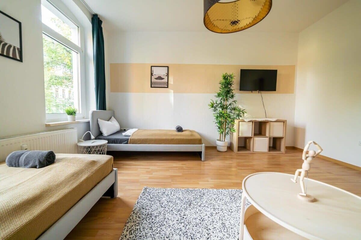 Una camera da letto moderna con un letto, una scrivania, una televisione e una finestra con tende.