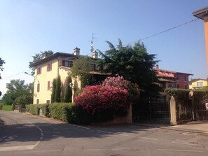 A residential building with a gated entrance, a driveway, and a large bush with pink flowers. - holiday home among the vineyards (Centenaro)