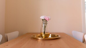 Une table en bois sur laquelle repose un vase en verre transparent contenant des fleurs roses, le tout posé sur un plateau doré.