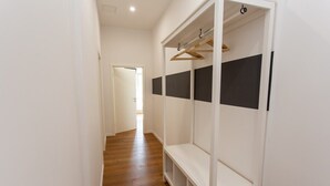 A hallway with a wooden floor, a white closet with black panels, and a door at the end.