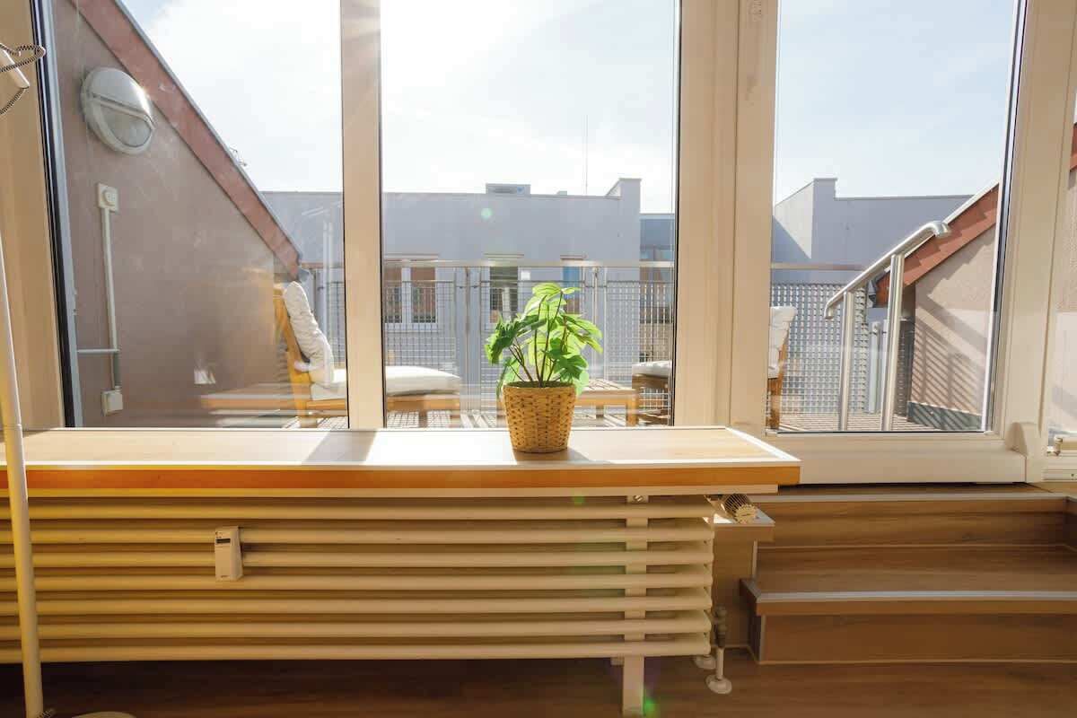 Un balcon avec un banc en bois, un pot de fleurs et une vue sur le paysage urbain.