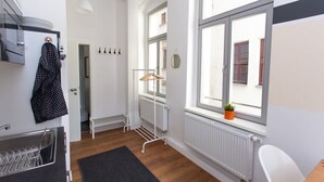 A modern apartment with a kitchenette, a drying rack, a radiator, and a window with a plant. - FullHouse | Halle | M14 Michelangelo | Zentrum (Halle (Saale))