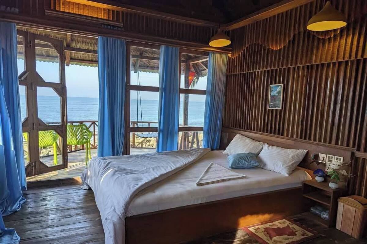 Une chambre avec un lit, des murs en bois et une vue sur la mer.