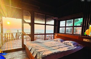 Una habitación con cama, ventanas amplias y vista al mar.