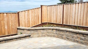 Un espace patio bordé de pierres et entouré d’une clôture en bois.