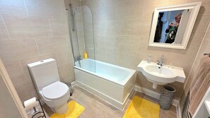 Une salle de bain moderne équipée de toilettes, d’une baignoire et d’un lavabo.