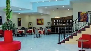 A spacious lobby with a high ceiling, a staircase, and a seating area with red chairs. - Ambiance Hotel Baku (Baku)