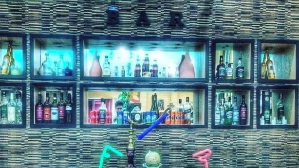 A bar area with shelves of various liquor bottles, a hookah, and several drinks with straws. - Ambiance Hotel Baku (Baku)