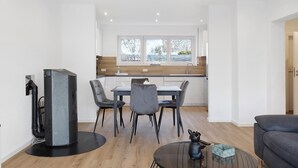 A modern living space with a dining area, kitchen, and a sofa. - Apartment 1 with Private Terrace, Shared Garden, and Wi-Fi (Bad Dürrheim)