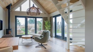 Un salon moderne doté d’un haut plafond, d’une cheminée, d’un canapé, d’une table basse et d’un escalier.