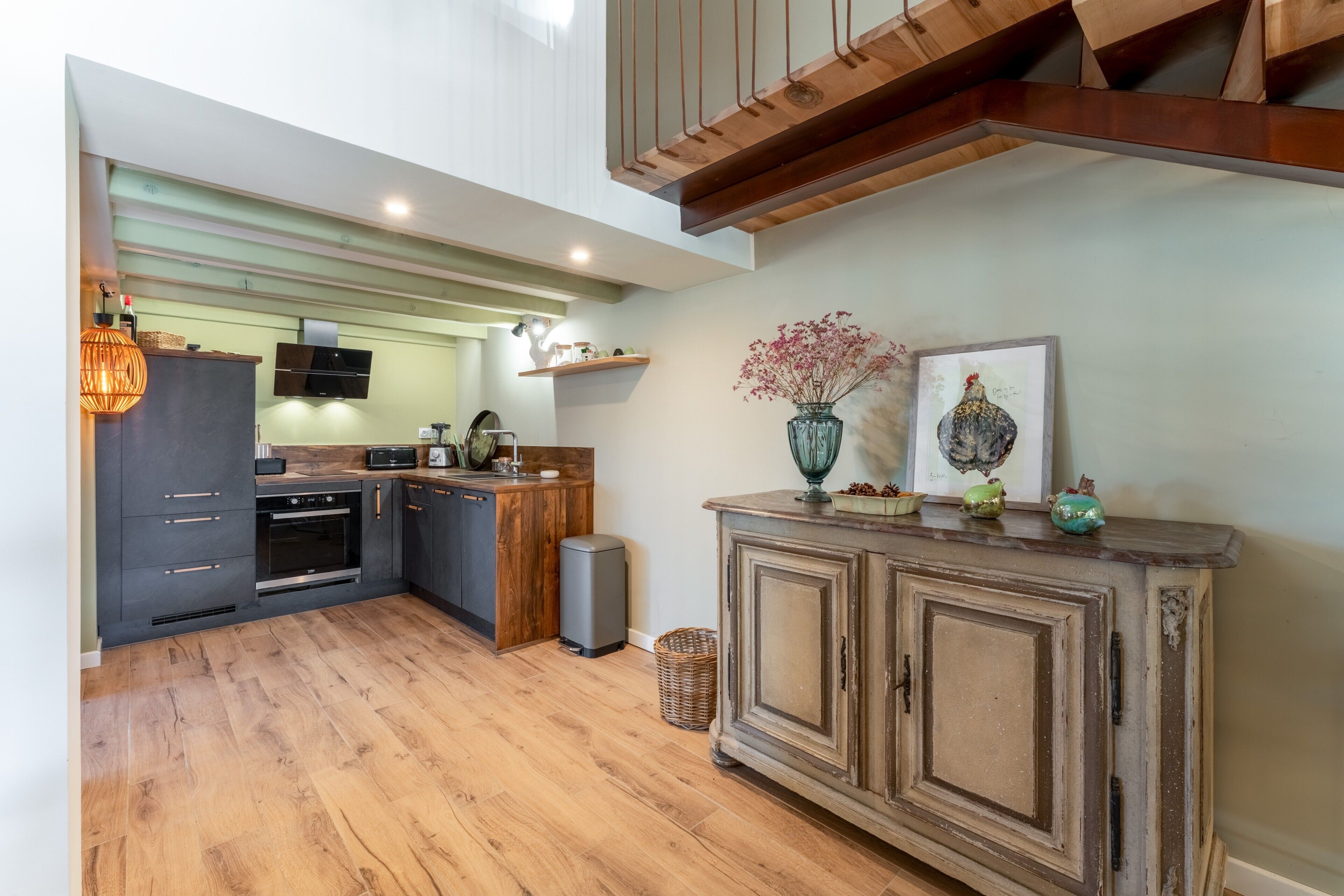 Une cuisine moderne avec des meubles de rangement aux couleurs sombres, un plan de travail en bois et un four encastré.