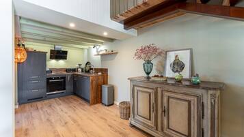 Une cuisine moderne avec des meubles de rangement aux couleurs sombres, un plan de travail en bois et un four encastré.