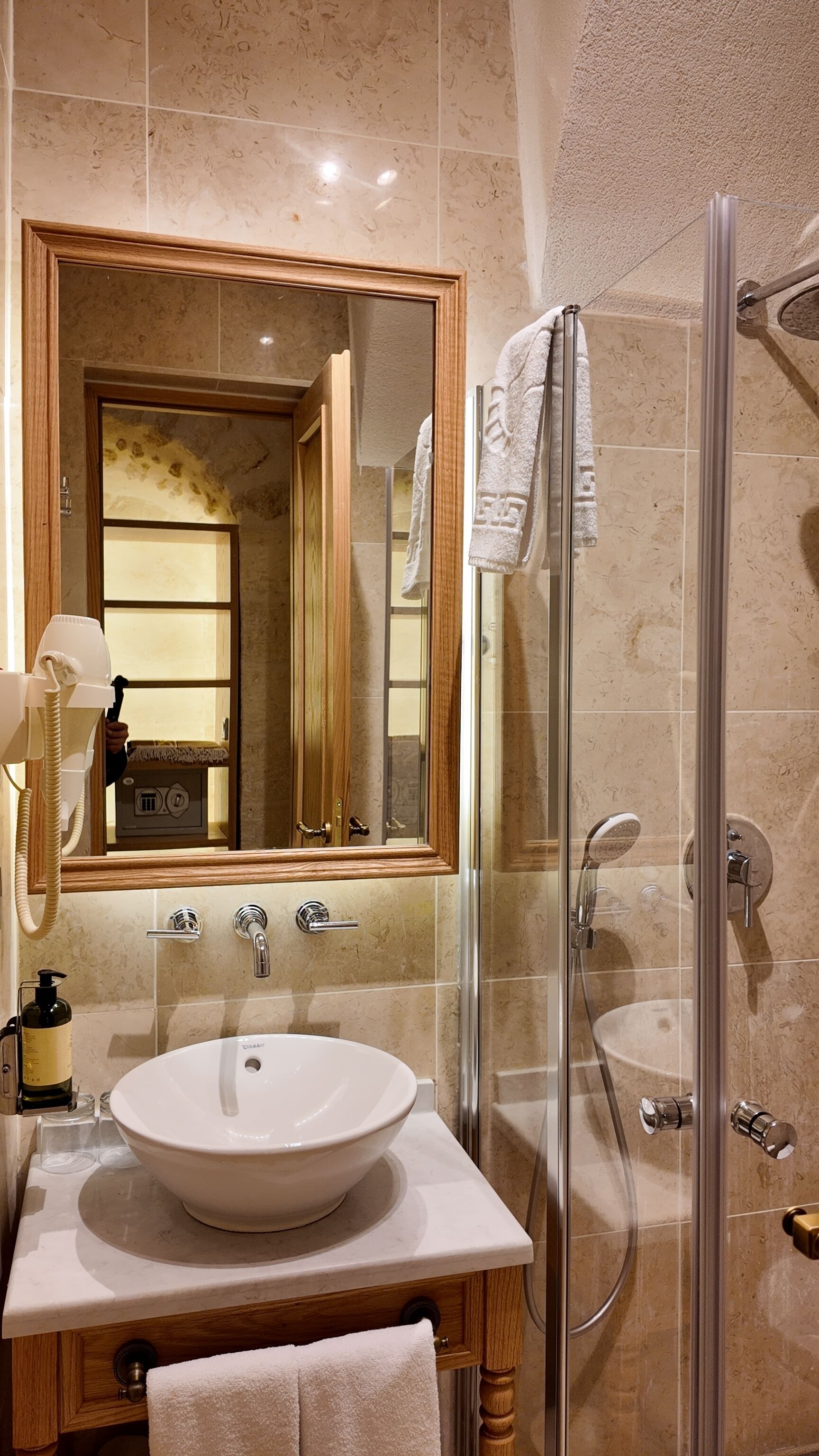 A bathroom with a large mirror, a sink, a glass shower enclosure, and a towel rack.