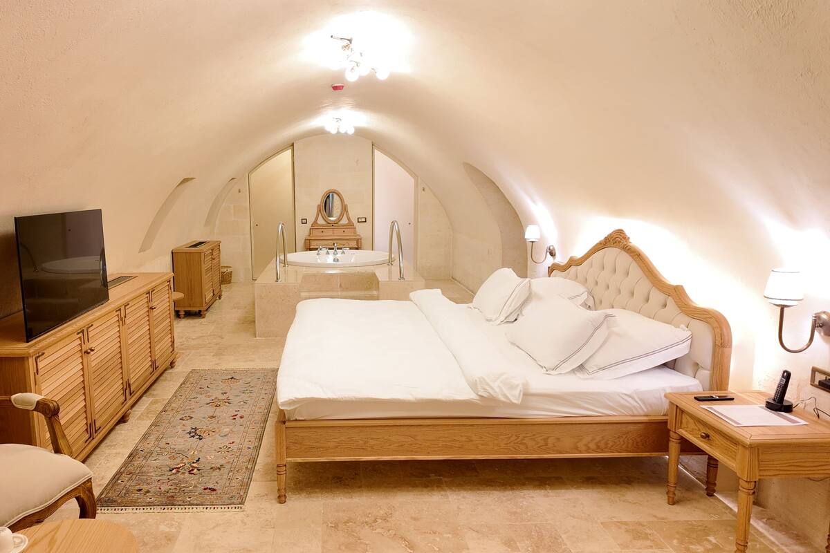 Un dormitorio con una cama grande, un aparador de madera, un televisor, una mesita de noche y un espejo.