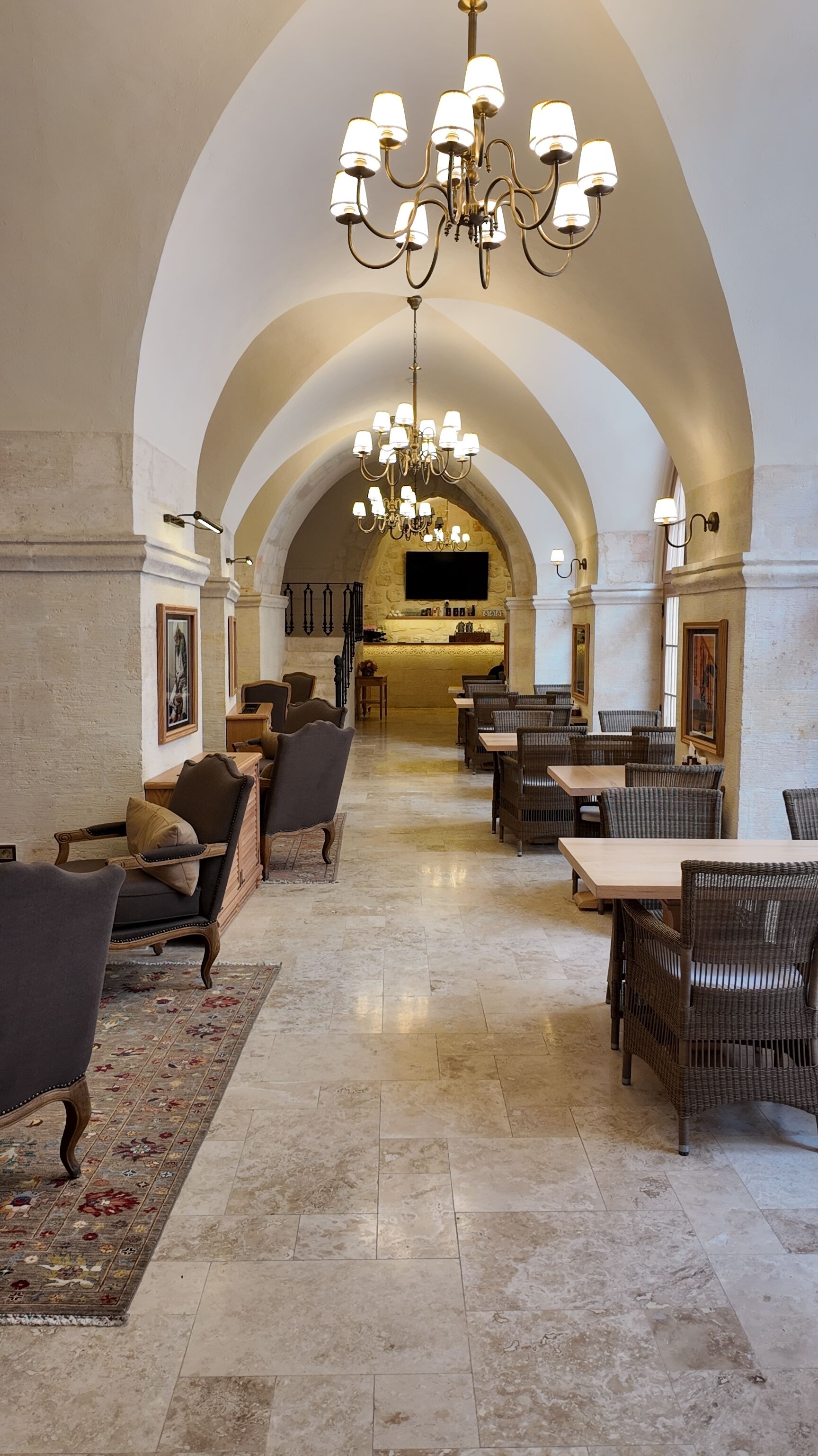 A spacious lobby with high arched ceilings, a central chandelier, and a reception desk.