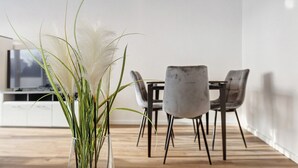 A dining area with a table and chairs, a vase with plants, and a TV in the background. - Apartment '2' with Shared Garden, Balcony, and Wi-Fi (Bad Dürrheim)