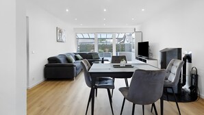 A modern living space with a dining area, sofa, TV, and fireplace. - Apartment '2' with Shared Garden, Balcony, and Wi-Fi (Bad Dürrheim)