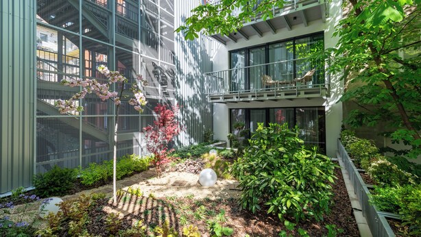 A modern building with a glass facade, surrounded by a landscaped garden with various plants and a spherical sculpture. - BUDAPEST DOWNTOWN RESIDENCE VH (Budapest)