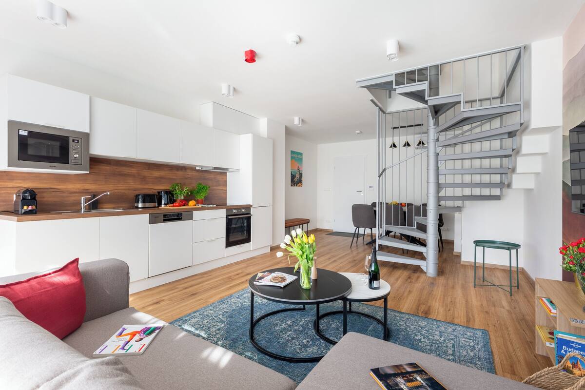 A modern apartment with a kitchen, dining area, and a spiral staircase.