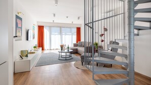 A modern living room with a staircase, a sofa set, a coffee table, and a dining area. - BUDAPEST DOWNTOWN RESIDENCE VH (Budapest)