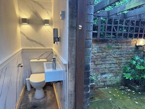 Ein kleines Badezimmer mit Toilette, Waschbecken und Marmorwänden.