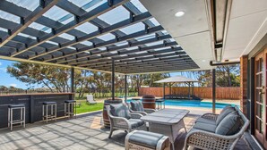 A covered patio area with outdoor furniture, a pool, and a wooden fence in the background. - Seabreeze Acres ~ Maslin Beach - Seabreeze Acres = Coastal Serenity! (Maslin Beach)