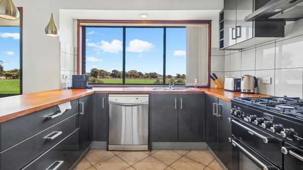 A modern kitchen with a dishwasher, stove, and large windows offering a view of the outdoors. - Seabreeze Acres ~ Maslin Beach - Seabreeze Acres = Coastal Serenity! (Maslin Beach)