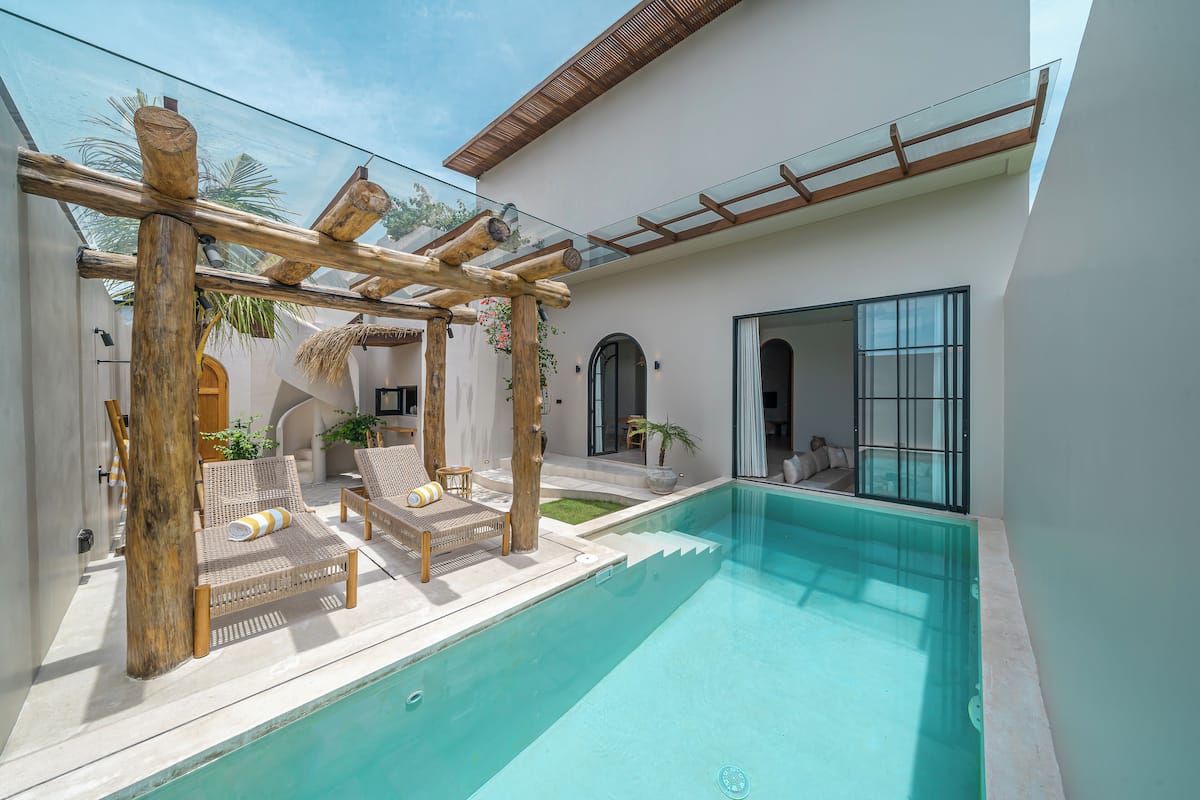 Un espace piscine extérieur moderne, agrémenté d’une pergola en bois, de chaises longues et d’une piscine à l’eau d’un bleu cristallin.