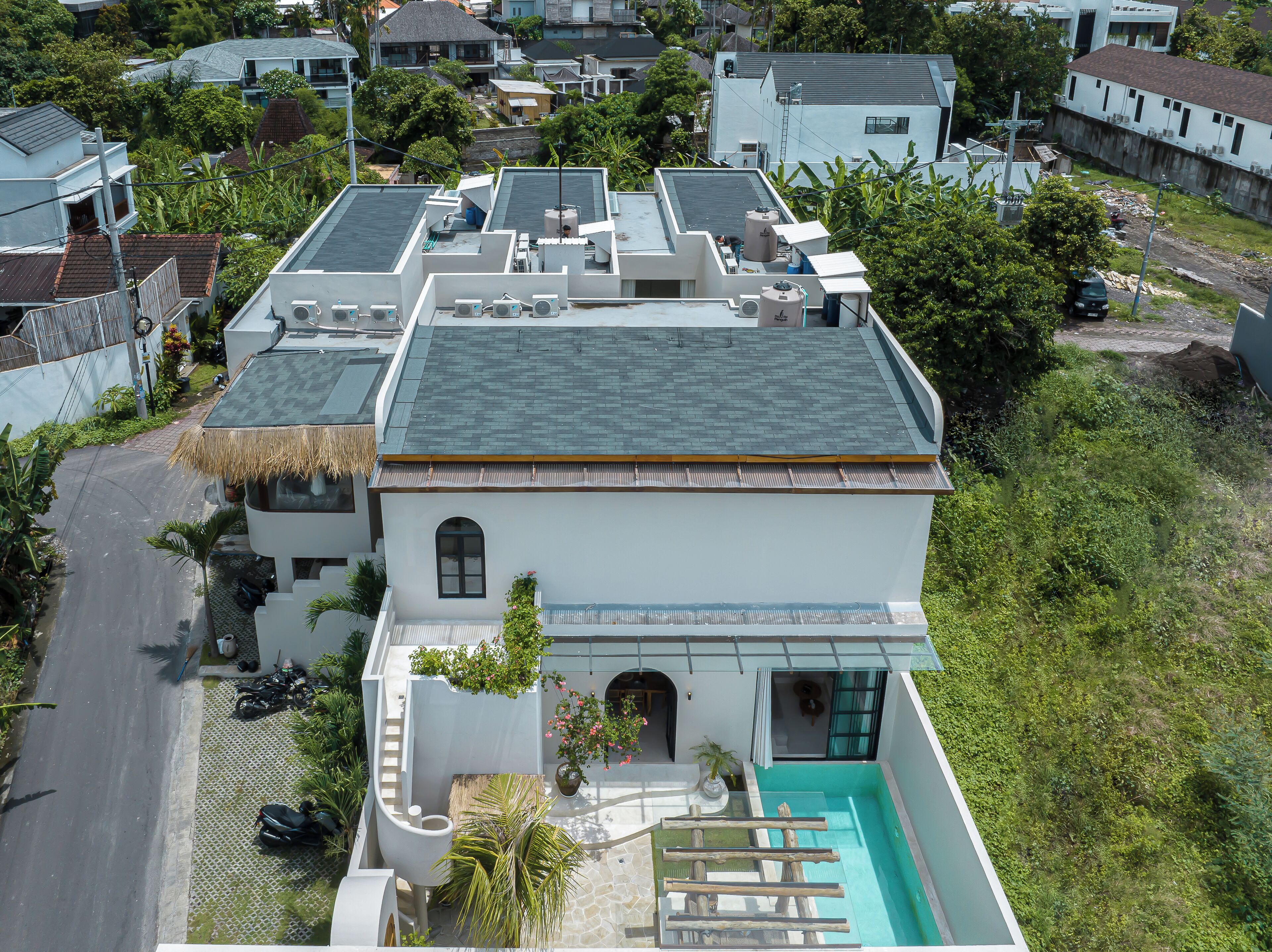 Une maison moderne dotée d’une piscine, de panneaux solaires et d’un toit de chaume.