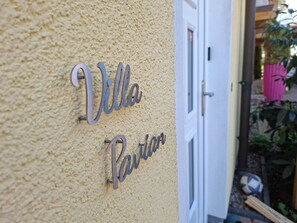Pared texturizada com uma placa de metal que diz 'Villa Pavillon'.